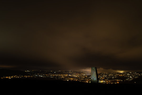 Trig point on Little Solsbury Hill overlooking Bath. Night view of the UNESCO World Heritage City of Bath, with stone used for cartographic triangulation in foreground