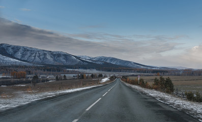 empty road in the countryside with trees in late autumn with snow