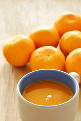 orange squeeze in cup and tangerine on wooden board
