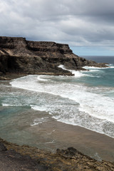 Wave splashing over a rock on the beach of Puertito de los Molinos on Fuerteventura. Canary Island, Spain