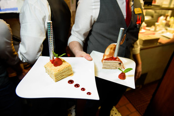 Waiter carries little pieces of cake with Bengal fires