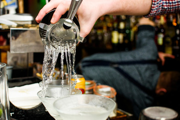 Man pours water in the glass for cocktail