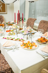 Tasty snacks served on white plates lie on dinner table