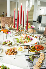 Red candles stands on dinner tables served with delicious dishes