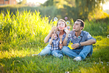 Naklejka na ściany i meble The family father, mother and son smiling and spend time together on the bright green grass.