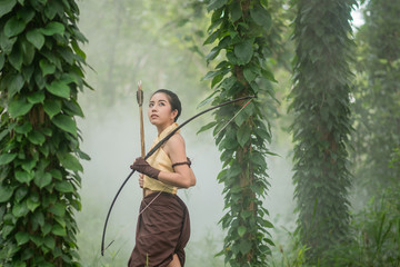 .Beautiful Thai woman archer with longbow and arrows in forest b