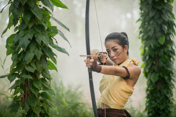 .Beautiful Thai woman archer with longbow and arrows in forest b