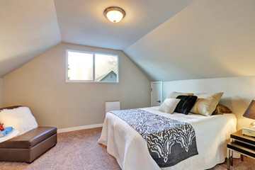 Attic bedroom with large bed and carpet floor.