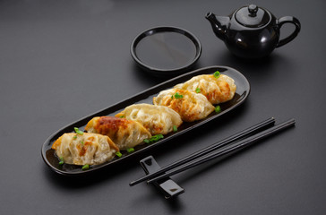 A plate of Japanese gyoza over black background