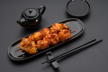 Chicken skewers on a black plate