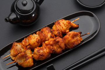 Chicken skewers on a black plate