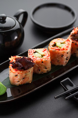 Sushi with shrimp and red tobiko in mamenori on a black plate