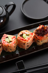 Sushi with shrimp and red tobiko in mamenori on a black plate