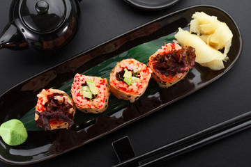 Sushi with shrimp and red tobiko in mamenori on a black plate