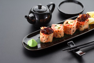 Sushi with shrimp and red tobiko in mamenori on a black plate