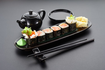 Salmon hoso maki on a black plate