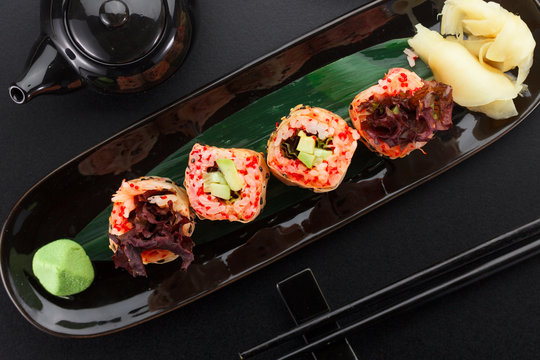 Sushi with shrimp and red tobiko in mamenori on a black plate