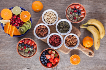 Smoothie  with fruits and berries on the grey wooden table, with variety of fruits and nuts around, selective focus; top view