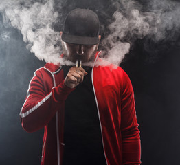 vaping man holding a mod. A cloud of vapor. Black background.