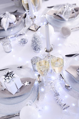 Fototapeta na wymiar bright white and silver new year eve or christmas table in a luxury restaurant with champagne
