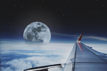 View through aircraft window. traveling by plane with beautiful aerial sky with full moon and stars...