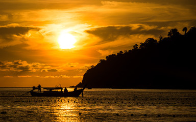 Sun setting behind longtail boat in Ko Lipe, Thailand