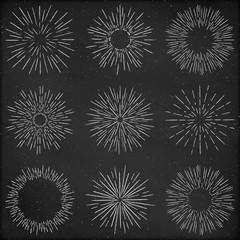 Set of hand drawn retro sunburst, fireworks or bursting rays design elements, stylized drawing with chalk. Grunge blackboard background.
