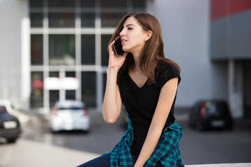 Portrait of urban fashionable girl using smart phone outdoors in the city