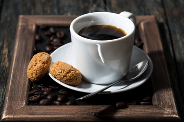 cup of black coffee and cookies on a tray