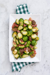 Brussels sprouts with chestnuts and bacon on white marble
