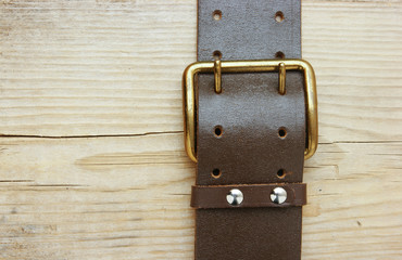 leather belt with a buckle on a wooden board