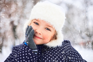 Portrait of a cute little girl in the snowy park.