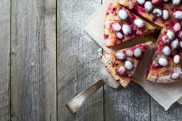 Homemade cranberry pie with walnuts, berries and powdered sugar. Top view. Space for text. Rustic style. Selective focus.