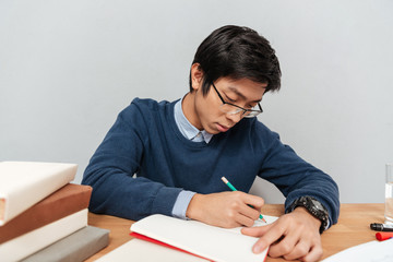 Asian student writing in notebook