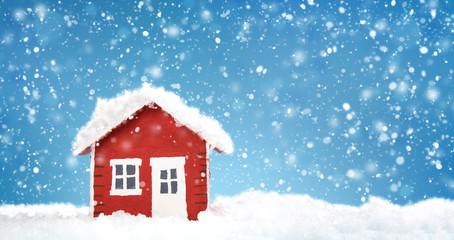 Small red house model covered with snow in winter