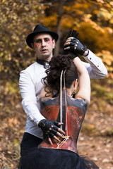 Young man imitates violin play painted viola on woman's back