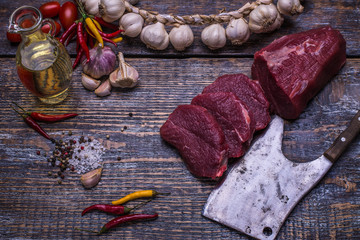 Raw Beef Steak, salt, pepper, garlic, rosemary, olive oil  on the wooden board, background. 