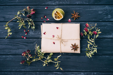 Autumn or winter composition of dried flowers, spices and wrapped gift on wooden background. Top view, flat lay, copy space.
