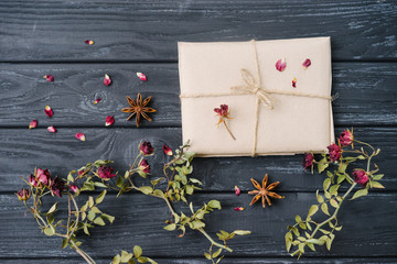 Autumn or winter composition of dried flowers, spices and wrapped gift on wooden background. Top view, flat lay, copy space.