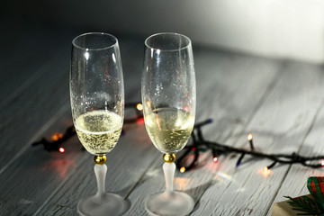 Obraz premium Two glasses of champagne and garland on a white floor
