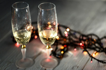 Cold champagne flutes stand on wooden floor behind Christmas gar