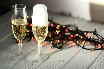 Two glasses of champagne and garland on a white floor