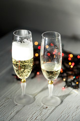 Champagne with foam in a glass standing behind Christmas garland