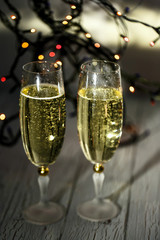 Sparkling glasses with champagne stand on white wooden floor