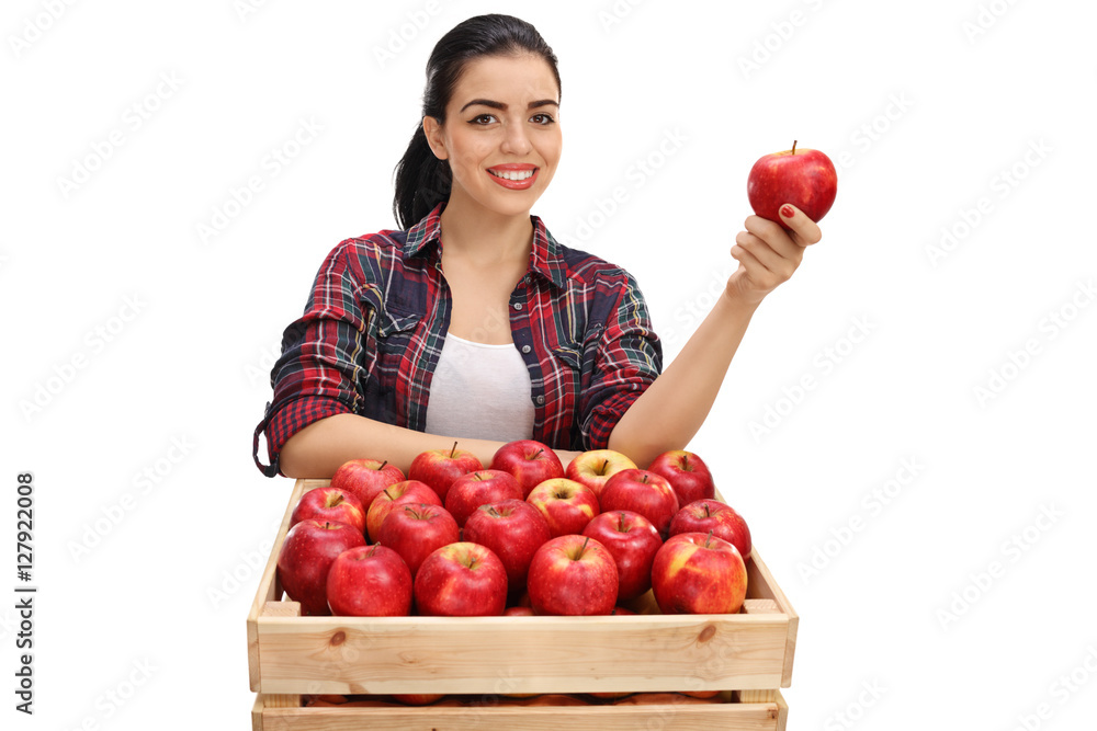 Canvas Prints cheerful female farmer holding an apple behind a crate full of a