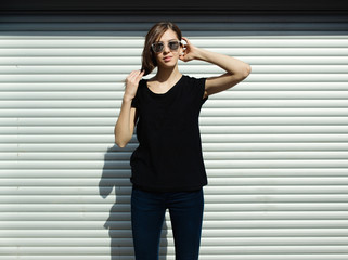 Portrait of girl in rock black style, standing outdoors in the city against the silver metal urban wall