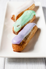 Eclairs on a white wooden background, vertical, selective focus
