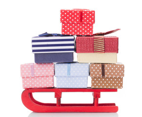 Fototapeta na wymiar Closeup of a red sled full of gift boxes, isolated on white back