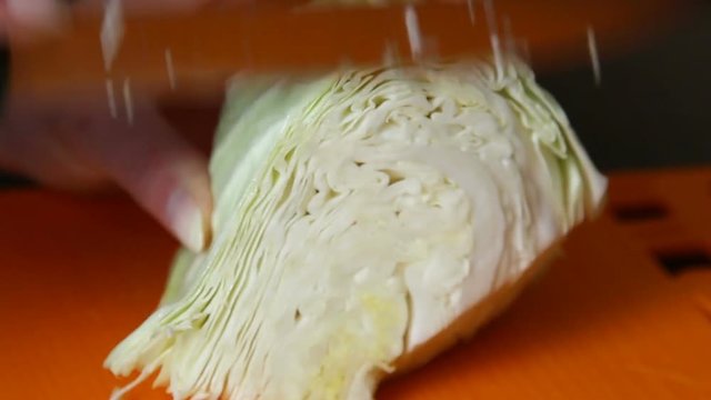 Woman is cutting cabbage close-up in the kitchen