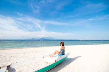 Happy sexy young woman in blue dress and sunglasses posing on Indonesian beach. Indian ocean, Beautiful blissful woman in blue dress enjoying tropical beach and indonesian summer vacation. Enjoying